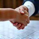 Two people shaking hands over architectural plans.